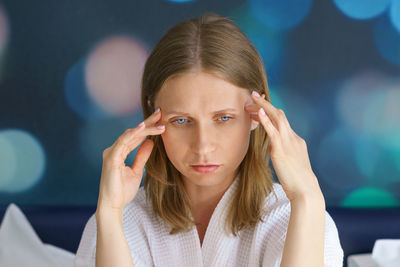 Portrait of a woman with a headache, holding her hands at her temples