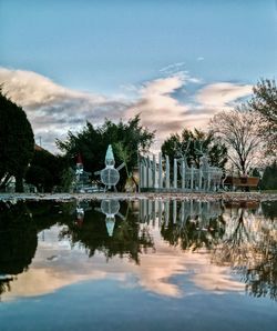 Reflection of trees in lake against cloudy sky