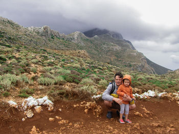 Portrait of father and son on mountain against cloudy sky