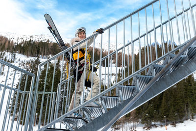 Low angle view of man on snow covered railing