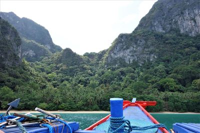 Boats moored on river by mountains against sky