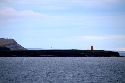 Lighthouse by sea against sky