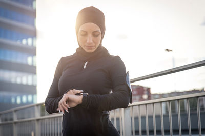 Beautiful woman wearing hijab standing against building during sunrise