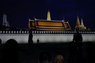 People at temple against sky at night