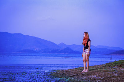 Woman standing at beach against sky