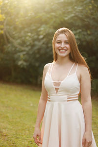 Portrait of smiling woman wearing dress while standing on field