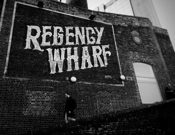 Low angle view of text on wall against building