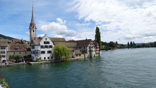 View of buildings by canal against sky in city