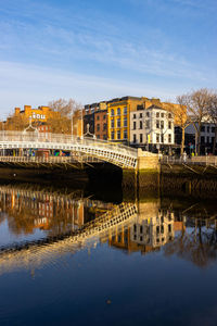 Bridge over river by buildings against sky in city