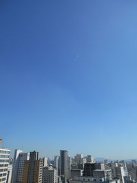 Buildings in city against clear blue sky