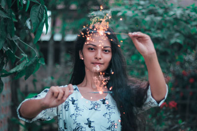 Portrait of young woman standing against plants