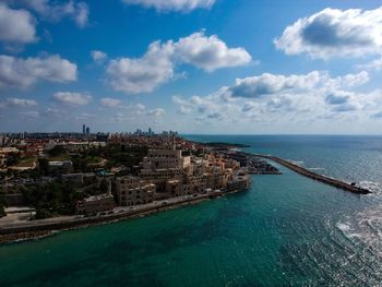 Aerial view of buildings in sea against cloudy sky