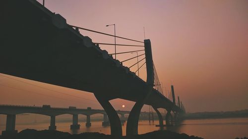 Silhouette bridge against clear sky during sunset