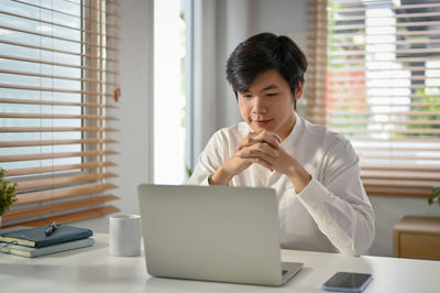 Young man using laptop while sitting on table