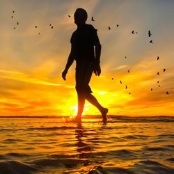 Silhouette man standing on beach at sunset