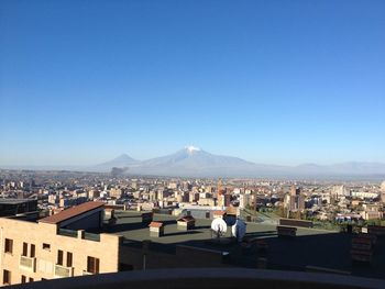 Buildings in city against clear blue sky