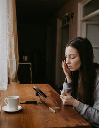 Side view of young woman sitting at home
