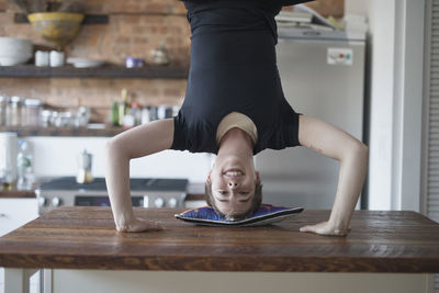Transgender person doing a handstand on their kitchen counter