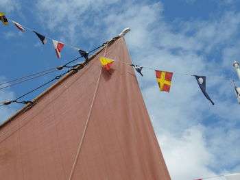 Low angle view of flags hanging on mast against sky