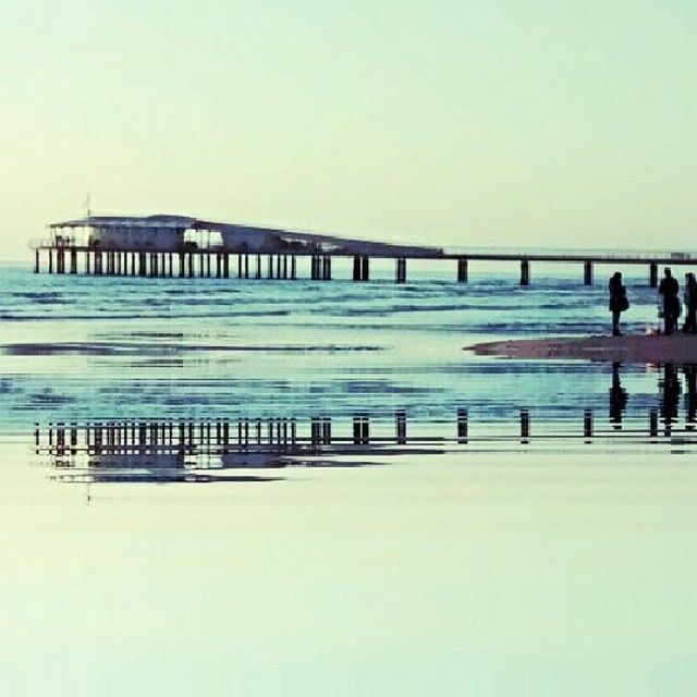 clear sky, copy space, water, sea, built structure, architecture, railing, men, pier, person, walking, lifestyles, beach, horizon over water, bridge - man made structure, outdoors, leisure activity, nature, large group of people