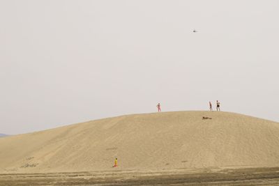 People on desert against clear sky