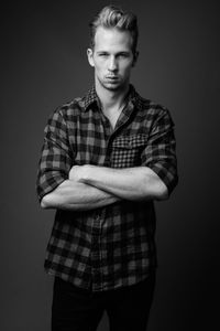 Portrait of young man standing against black background