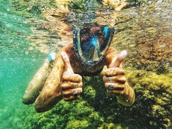 Portrait of woman showing thumbs up while swimming in undersea