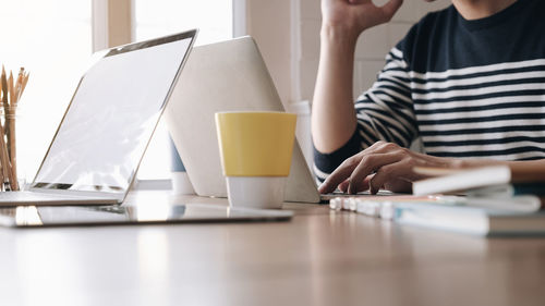 Midsection of woman using laptop on table