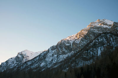 Low angle view of snowcapped mountains against clear sky