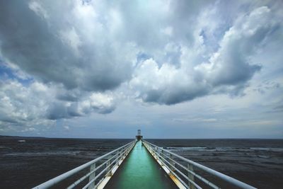 Pier over sea against cloudy sky