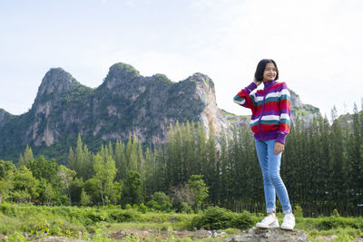 Portrait of young woman standing on mountain against sky