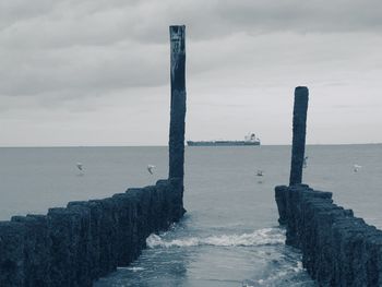 Wooden posts on sea against sky