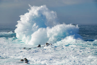 Huge waves crashing on sea against sky