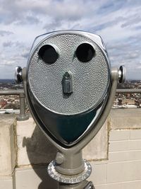 Close-up of coin-operated binoculars against cityscape