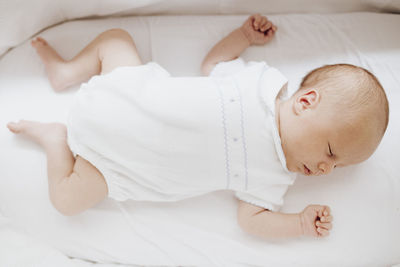 Cute baby boy sleeping on bed at home