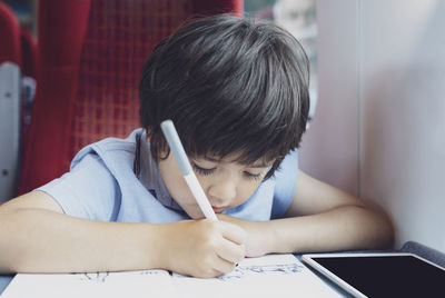 Portrait of boy holding book on table