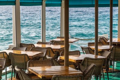 Empty chairs and tables in restaurant by sea