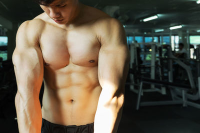 Shirtless muscular man flexing muscles at gym