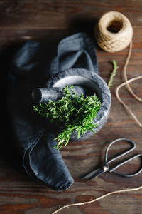 High angle view of mortar and pestle with herbs on table