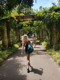 Full length rear view of woman walking on road