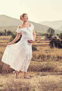 Pregnant woman walking on field against sky