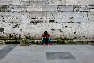 Woman sitting on sidewalk