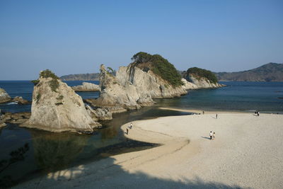 Rocks on beach against clear blue sky