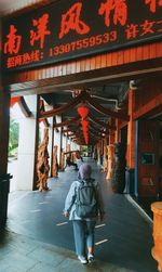 Rear view of women walking on footpath against building