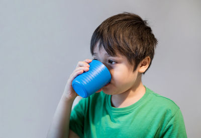 Portrait of boy holding camera over white background