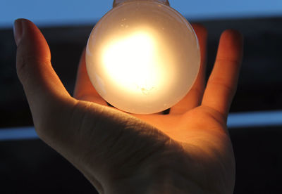 Close-up of hand holding illuminated lamp