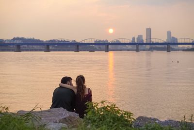 Rear view of man sitting on bridge in city