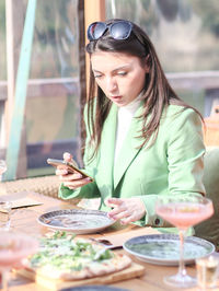 A beautiful girl in a mint suit looks at an empty plate with great surprise.