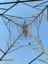 Low angle view of electricity pylon against clear blue sky