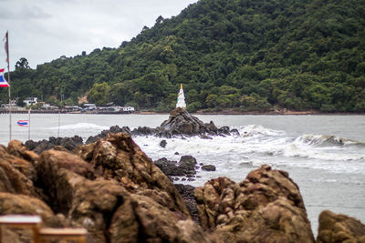 Scenic view of rocks by sea against sky